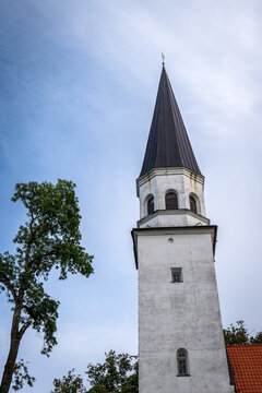 Historic White Church Tower and Dark Steeple Against Blue Sky