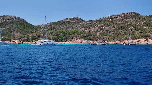 Panoramic view of the turquoise bay with a rocky coastline with yachts and boats off the coast of Spargi Island in the La Maddalena archipelago, Sardinia, Italy