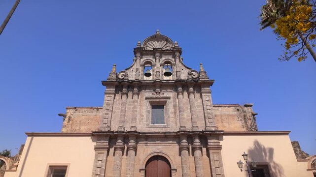 Historic stone facade of Di&oacute;cesis de Ciudad Guzman church with twin bells and ornate religious architecture in Ciudad Guzman, Zapotlan el Grande, Jalisco, Mexico, dolly in shot