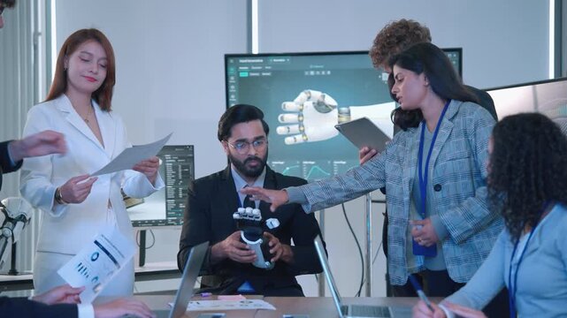 A diverse team of engineers and technology professionals discussing a robotic hand prototype during a collaborative research and development meeting in a modern laboratory.
