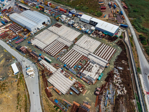 Aerial view of an industrial construction site featuring rows of stacked concrete beams, storage warehouses, and heavy equipment in Lemesos, Lemesos, Cyprus.