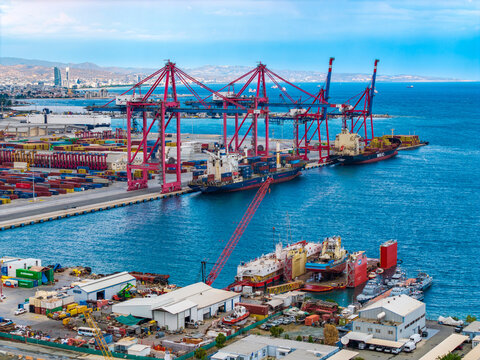 Aerial view of Limassol Port with large container ships, red gantry cranes, and cargo containers under a blue sky in Lemesos, Lemesos, Cyprus.