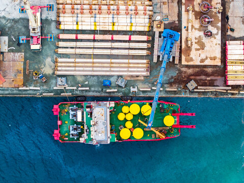 Aerial view of a work boat docked at Limassol Marina with construction materials and cranes on the pier in Lemesos, Lemesos, Cyprus.