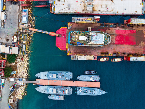 Aerial view of Limassol Marina showing various boats, tugs, and industrial vessels docked at the pier with clear blue water and concrete quays in Lemesos, Lemesos, Cyprus.
