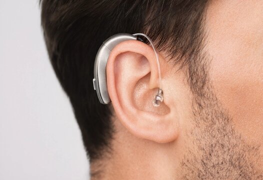 A man wearing a discreet behind-the-ear hearing aid device to improve hearing health and audio communication