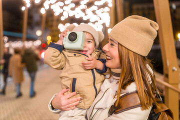 Obraz premium Mother and son enjoying christmas lights holding camera