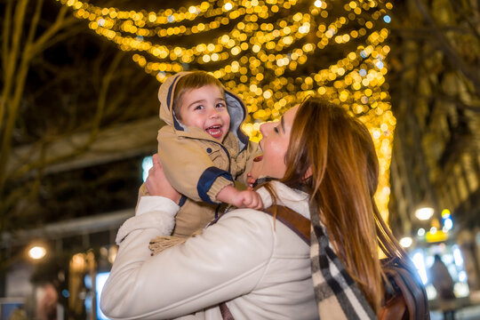 Mother and son enjoying holiday lights in city at night