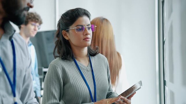 Diverse technology professionals collaborating during an engineering presentation in a modern office, with team members reviewing information and discussing project ideas.
