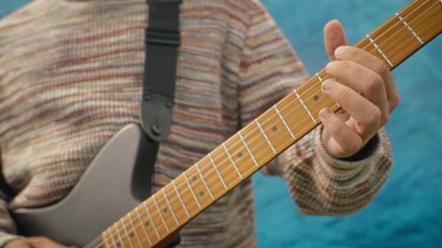 Musician playing electric guitar chords on fretboard and strumming strings. Clip suitable for music education platforms, indie band marketing, and lifestyle projects
