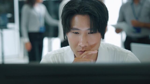Young technology professional concentrating on a computer screen in a modern office, representing data analysis, software development, engineering research, and focused knowledge work.
