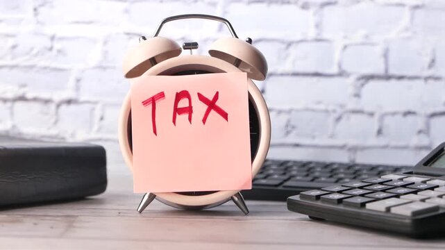 Alarm clock with sticky note reminder tax time and calculator on desk