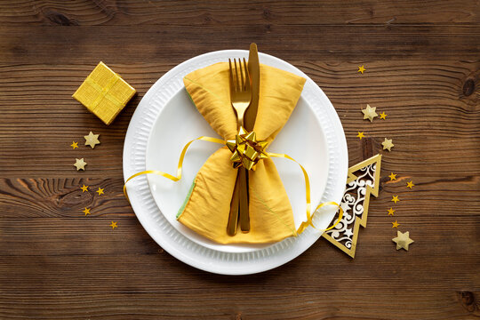 Festive Christmas table setting with yellow and gold colored decoration. Top view