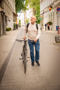 Confident senior man with his bike walking down a street in Budapest