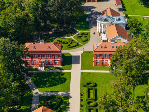 Aerial view of Raudondvaris Manor featuring historic red-brick buildings, manicured gardens, and lush green trees in Raudondvaris, Kauno apskritis, Lithuania.