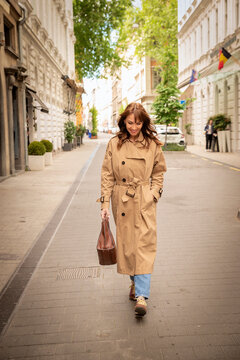 A middle-aged woman with brown hair walking down a street in Budapest