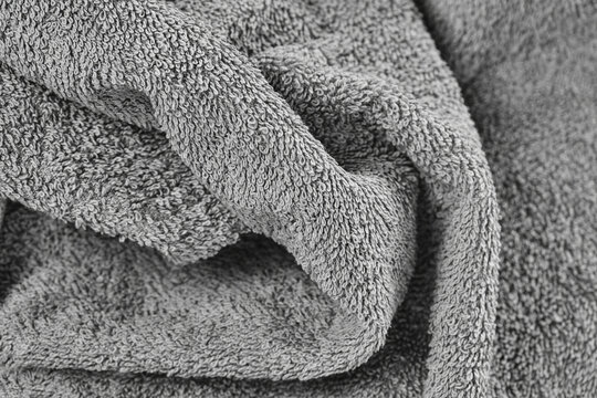 Close-up of folded gray terry cloth towel with soft looped pile texture and deep folds, cozy textile background