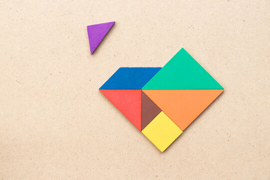 Color tangram puzzle wait for fulfill to heart shape on wood table