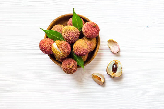 Exotic lychee fruit with green leaves in wooden bowl, top view. Healthy vegetarian meal