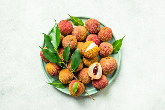 Exotic lychee fruit with green leaves on plate, top view. Healthy vegetarian meal