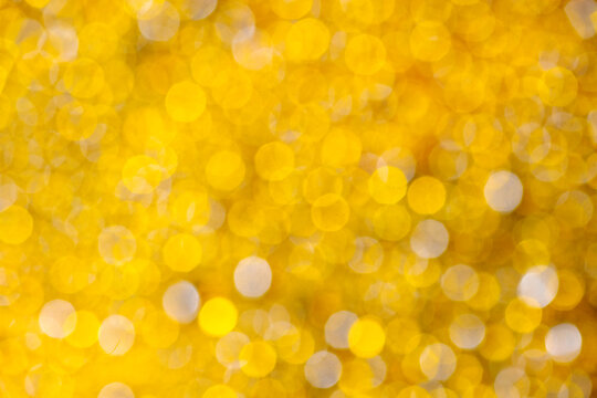 Abstract golden yellow bokeh background with sparkling, out-of-focus festive lights. Abstract holiday illumination and decoration background