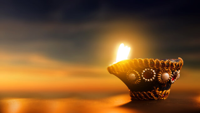 Decorated traditional Indian diya lamp glowing brightly at sunset during the Diwali festival of lights. Diwali festival celebration
