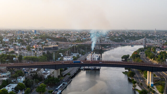 Aerial view of the Ozama River with the Juan Pablo Duarte and Juan Bosch bridges, urban infrastructure, and dense city buildings in Santo Domingo, Distrito Nacional, Dominican Republic.