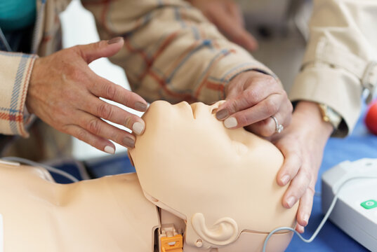 Hands performing CPR on a medical dummy during a training session