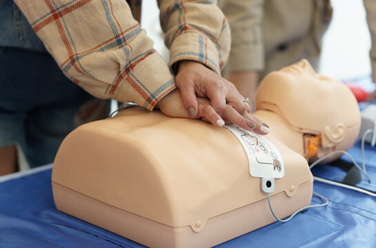 Hands practicing CPR on a training mannequin