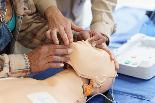 Latina woman learning the CPR technique on a mannequin during a first aid course.