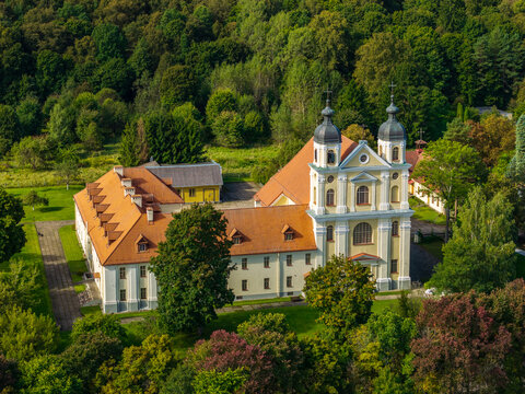Aerial view of the Church of the Visitation of the Blessed Virgin Mary with twin towers and orange roof, surrounded by lush green trees in Vilnius, Vilnius County, Lithuania.