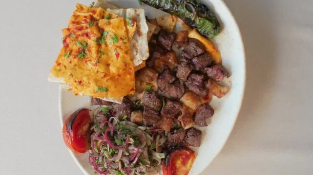 Traditional Turkish Shish Kebab served with grilled vegetables, pita bread, and onion salad