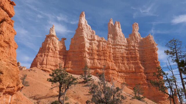 Stunning red rock hoodoo formations reaching towards bright blue sky with wispy clouds in bryce canyon national park, utah. This iconic american landmark showcases incredible natural geology