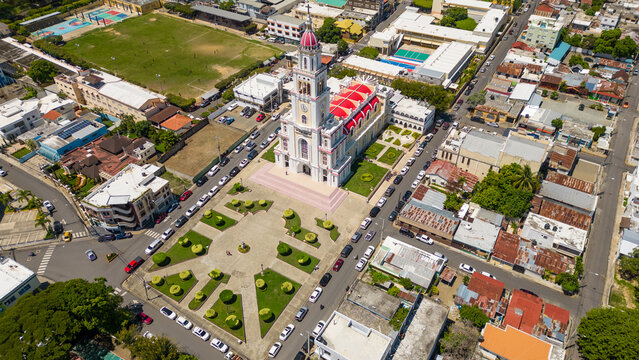 Aerial view of the Iglesia Sagrado Corazon de Jesus with its distinctive red roof and surrounding plaza in the city of Moca, Espaillat Province, Dominican Republic.