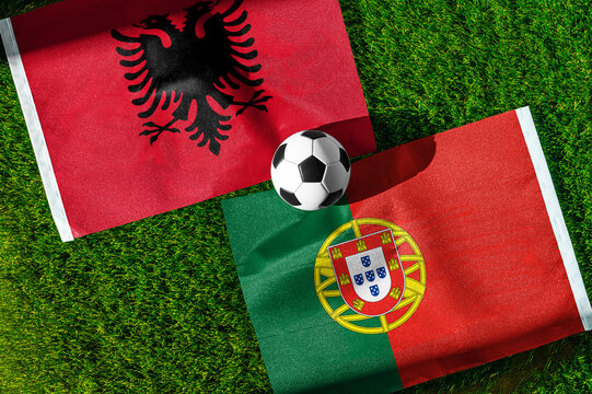 Albania vs. Portugal football match. National flags on green grass with soccer ball in the middle. Football background for international match.
