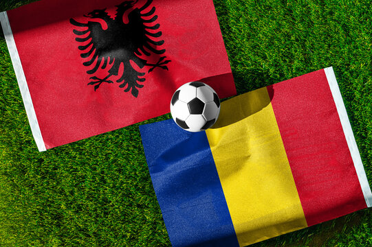 Albania vs. Romania football match. National flags on green grass with soccer ball in the middle. Football background for international match.