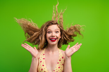 Obraz premium Joyful young woman with blonde hair wearing a floral top poses in front of a vibrant green background