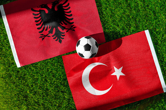 Albania vs. Turkey football match. National flags on green grass with soccer ball in the middle. Football background for international match.