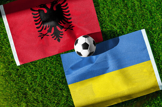 Albania vs. Ukraine football match. National flags on green grass with soccer ball in the middle. Football background for international match.