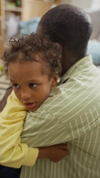 Vertical video of African American father embracing young son at home. Clip ideal for parenting counseling, mental wellbeing campaigns, family insurance ads