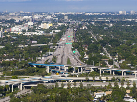 Aerial view of Interstate 95 Express highway interchange with multi-level overpasses, surrounding urban greenery, and city skyline in Miami, Florida, United States.