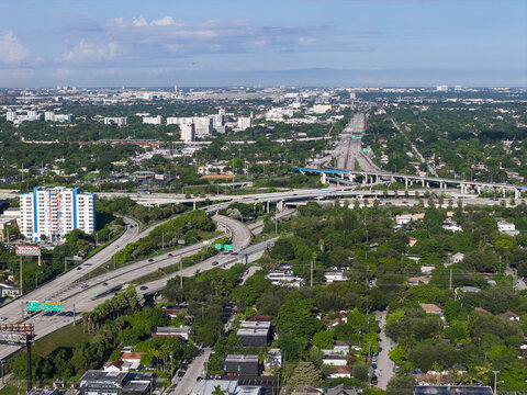 Aerial view of Interstate 95 Express highway interchange with surrounding urban landscape, lush greenery, and residential buildings in Miami, Florida, United States.
