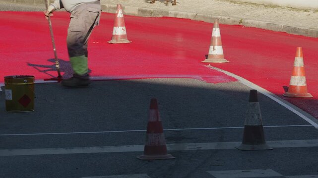 Process of painting for speed restricting road surface marking with red paint in residential areas.