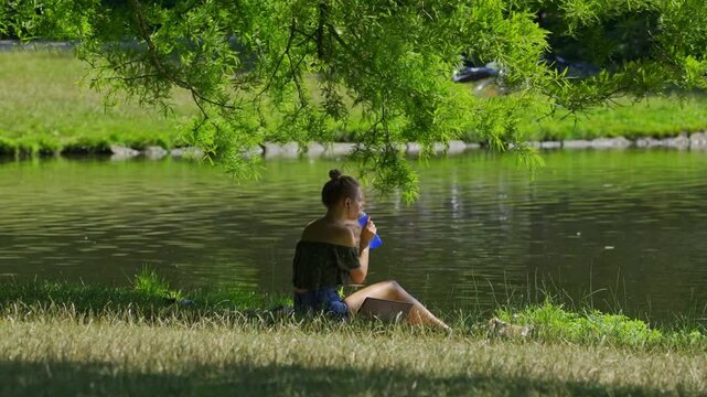 A young woman drinking water in a park during a heatwave caused by climate change.
