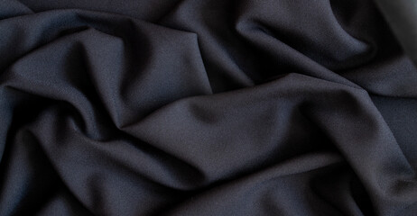 Fototapeta premium Crumpled black fabric texture with soft drapery and waves