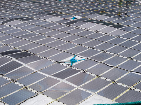 Aerial view of a circular floating solar power plant on the water surface with interconnected panels and blue mooring lines in Liabygda, More og Romsdal, Norway.