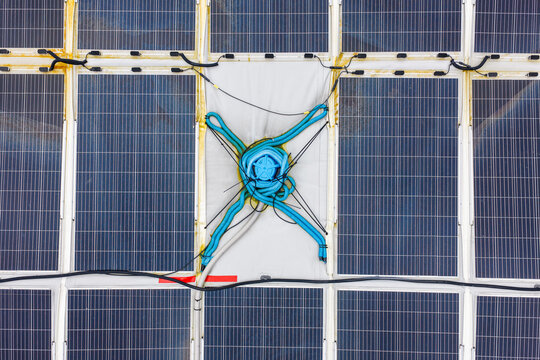 Aerial view of a circular floating solar power plant with blue conduits and wiring on the water surface in Liabygda, More og Romsdal, Norway.