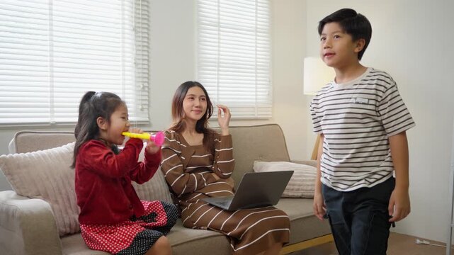 Stressed freelancer mother working from home with noisy and playful children disturbing her in the living room