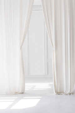 Elegant white sheer curtains framing a bright minimalist window, soft natural sunlight casting shadows across a clean interior floor, airy Scandinavian home decor, serene modern background