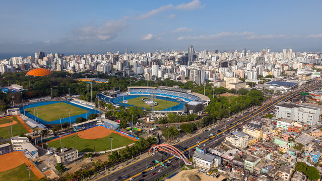 Aerial view of the Centro Olimpico Juan Pablo Duarte featuring sports stadiums and baseball fields amidst the urban skyline of Santo Domingo, Distrito Nacional, Dominican Republic.
