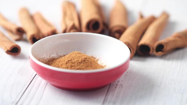 Close up slow motion footage of cinnamon sticks and powder in bowl